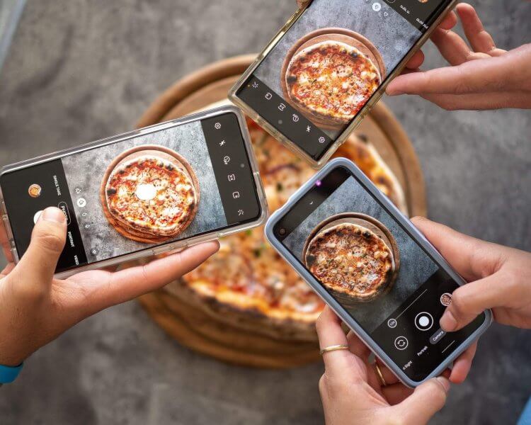 students taking a picture of a pizza purchased at one of the cheap places to eat in coventry